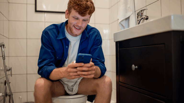 toilettes : une personne assise sur les toilettes avec un smartphone